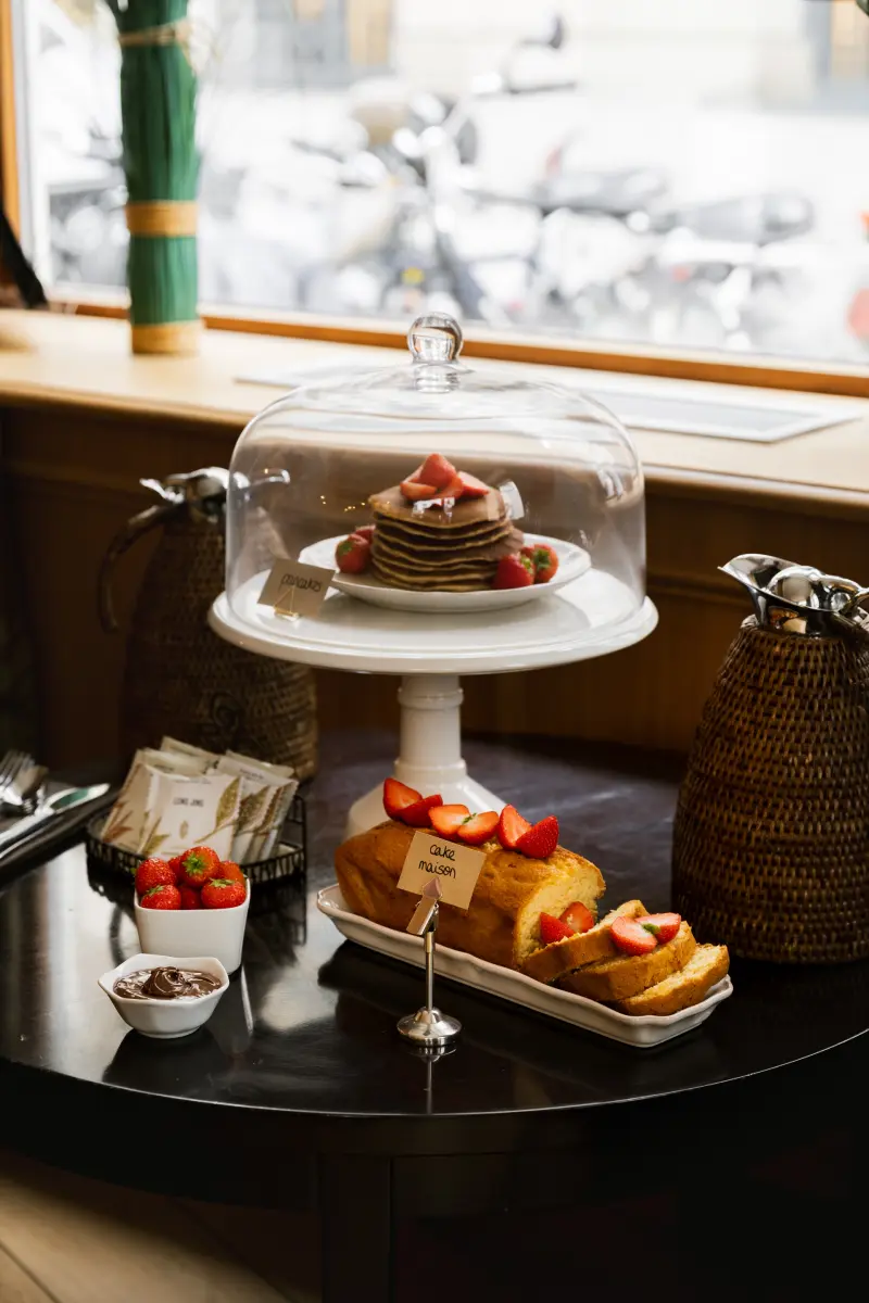 Buffet tea time : pancakes aux fraises sous cloche, cake maison tranche et fraises sur table ronde noire