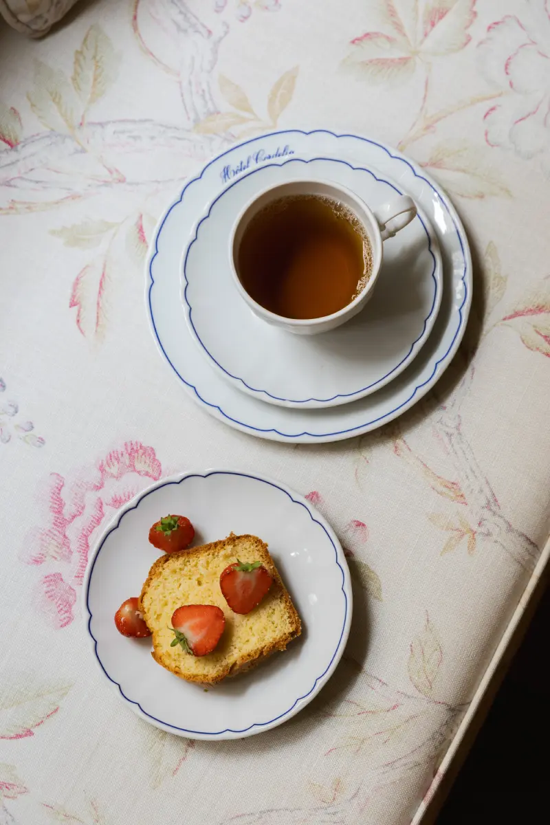 Vue de dessus : tasse de the Hotel Cordelia et assiette de cake aux fraises sur nappe fleurie